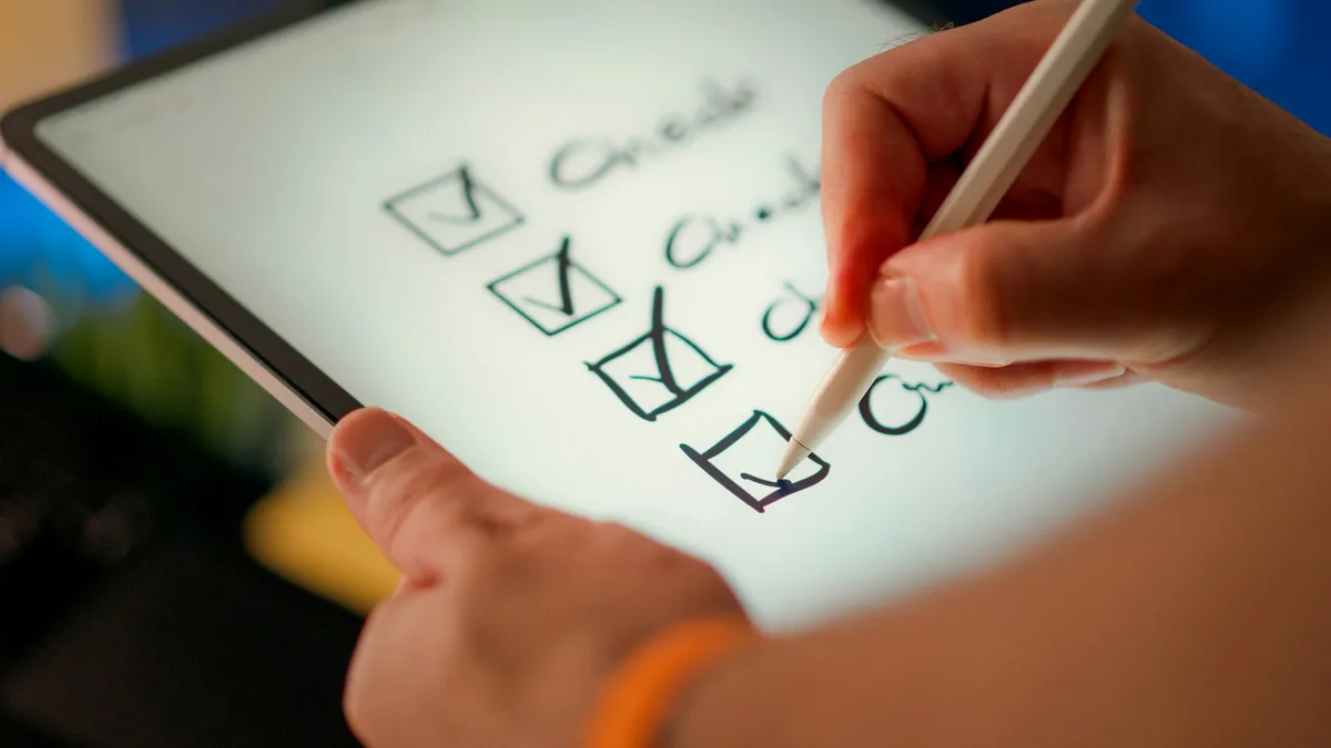 Eine Hand markiert Punkte auf einer Checkliste