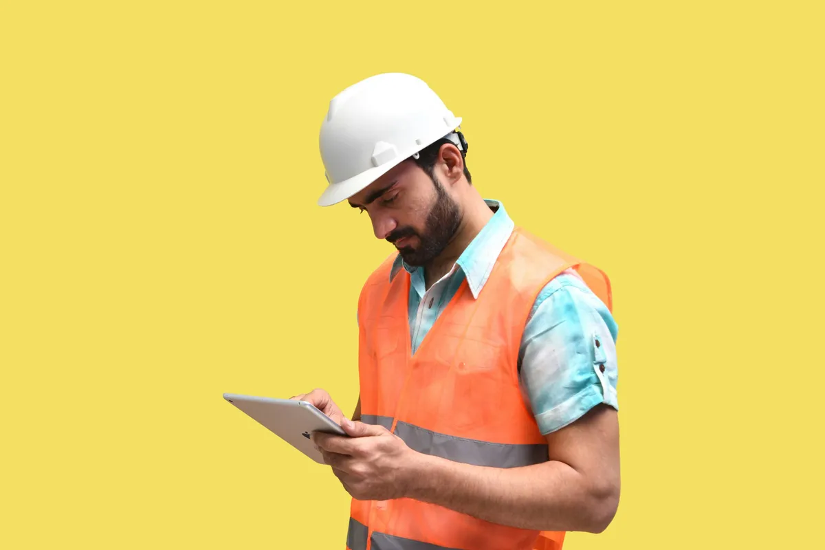 Eine Person mit Schutzhelm schaut auf ein Tablet