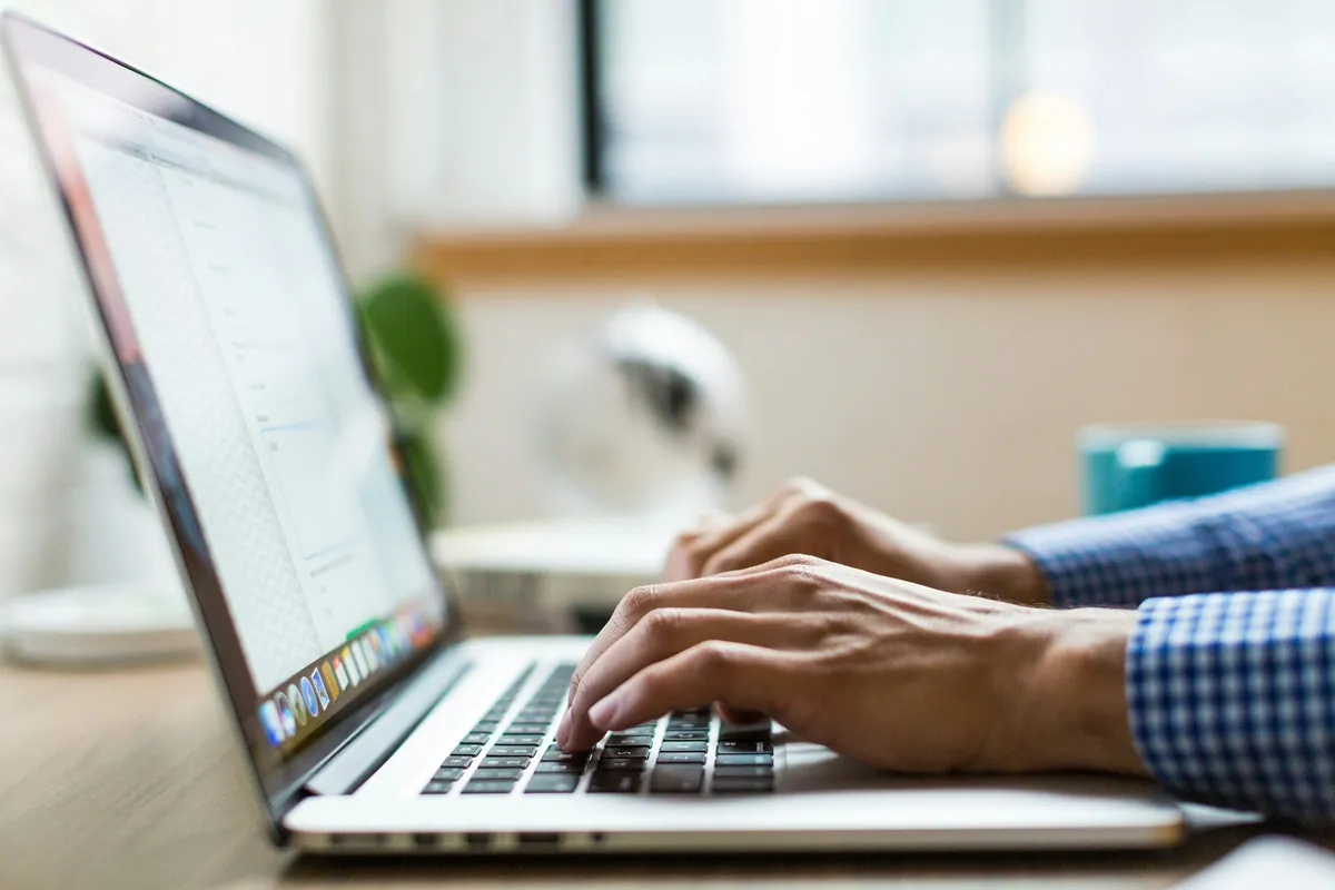 Person tippt auf einem silbernen MacBook
